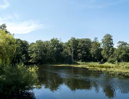 Fluss Eider in Achterwehr mit umgebenden Bäumen und klarem Himmel.
